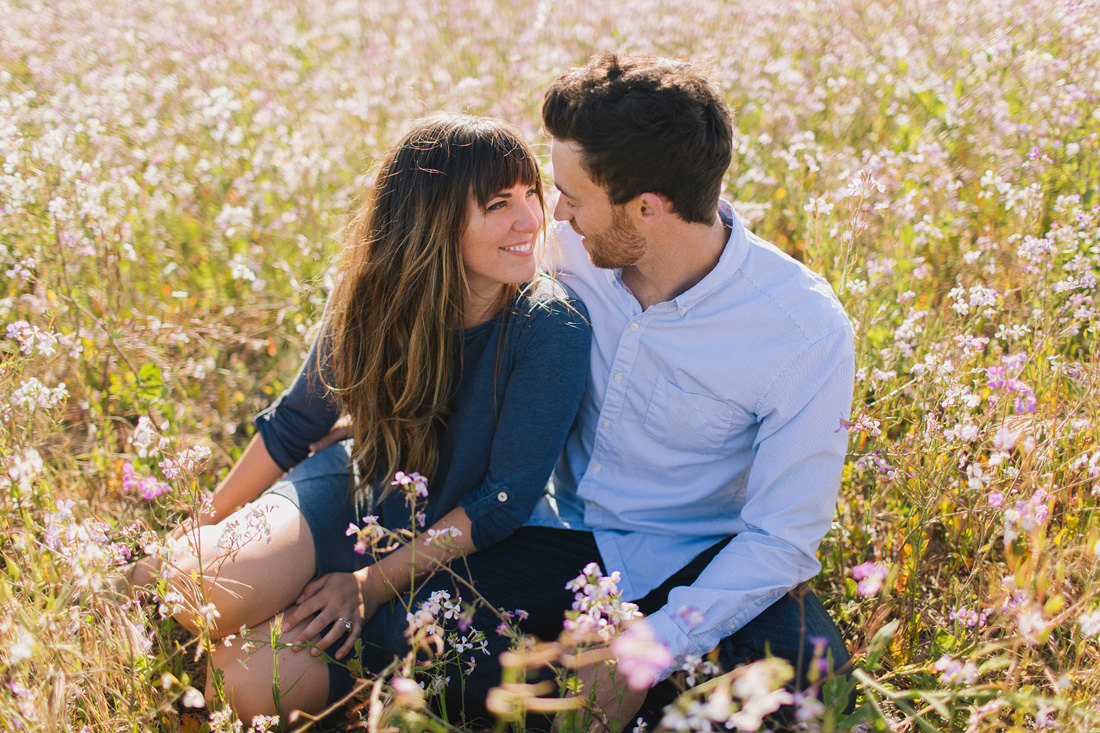 Engaged couple sitting in wildflowers