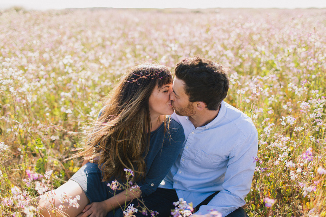 Engaged couple kissing in wildflower field